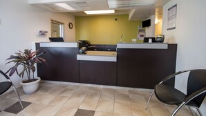 A reception area with a desk, chairs, a potted plant, and a wall-mounted phone. - Studio 6 El Paso, TX - East (El Paso)