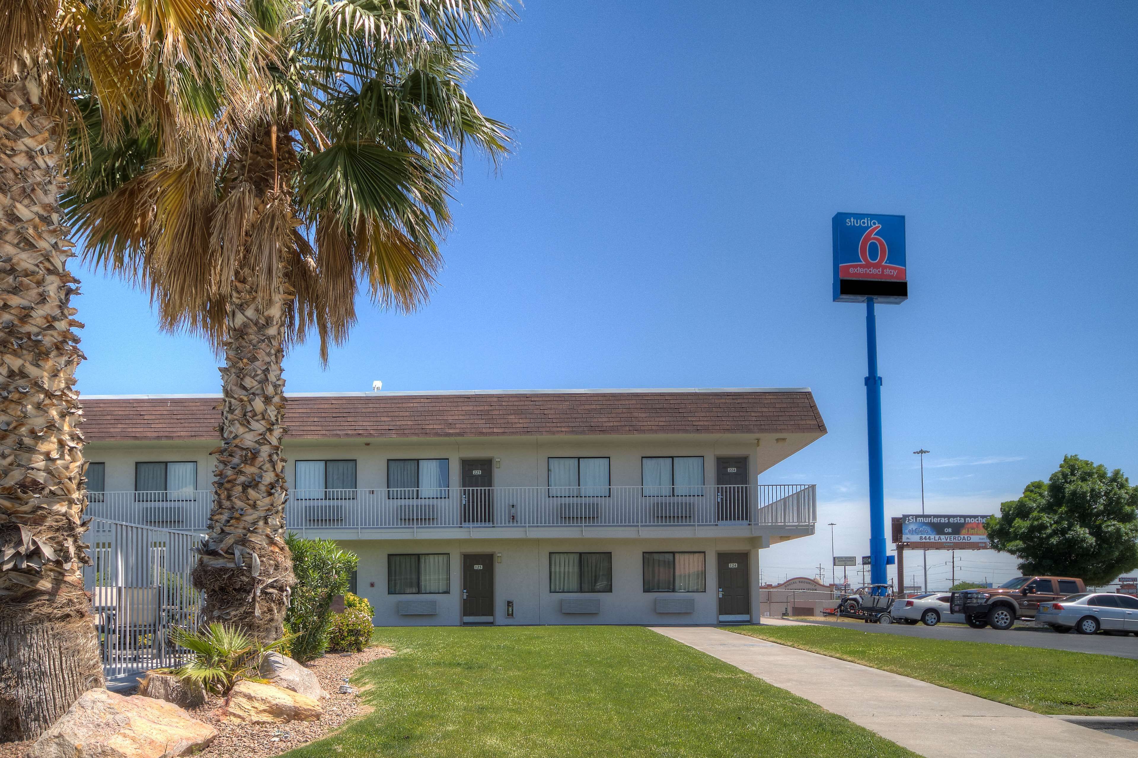 A motel with a two-story structure, a parking lot, and a sign indicating extended stay availability.
