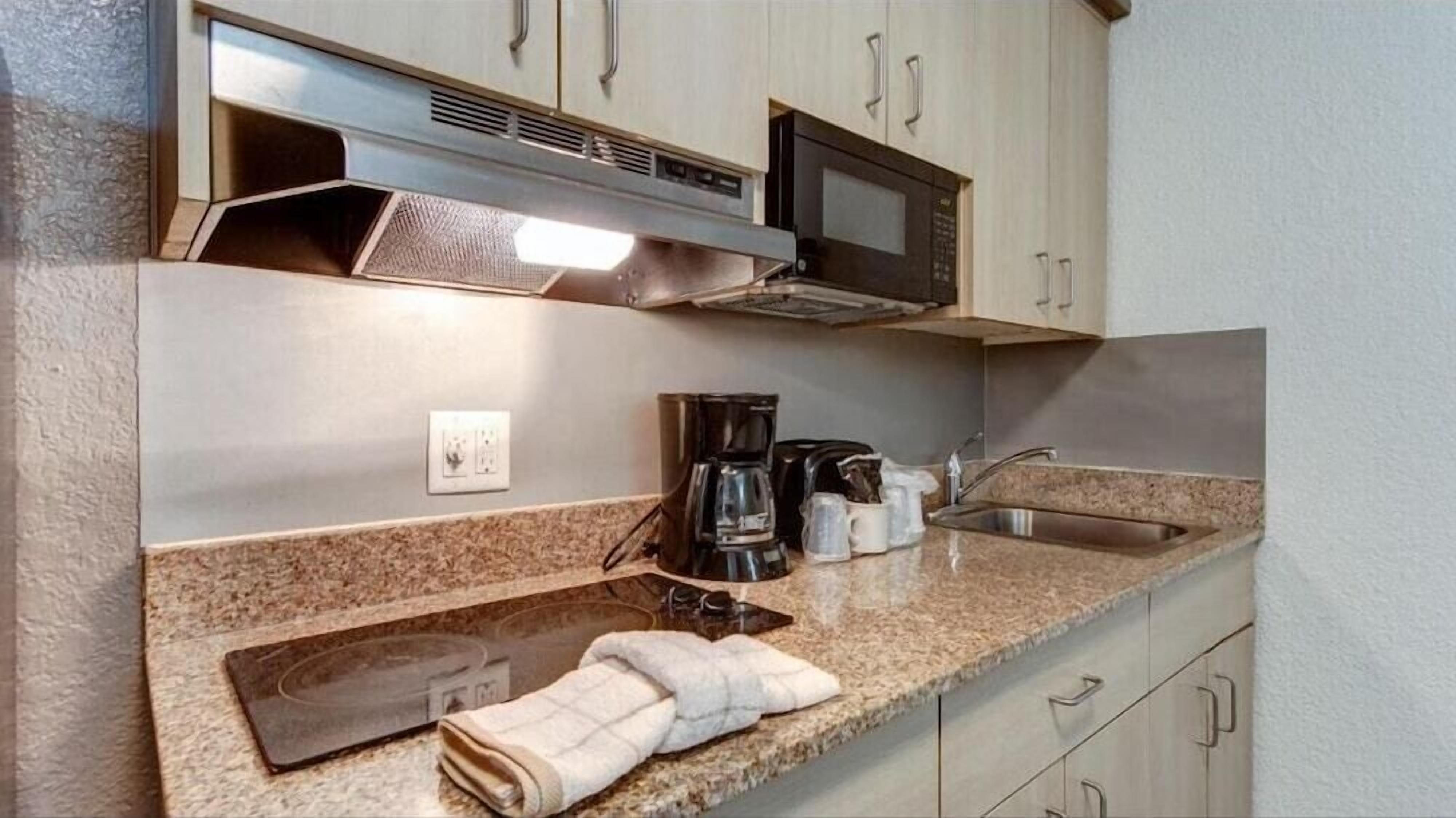 A kitchen with granite countertops, a microwave, a coffee maker, and a sink.