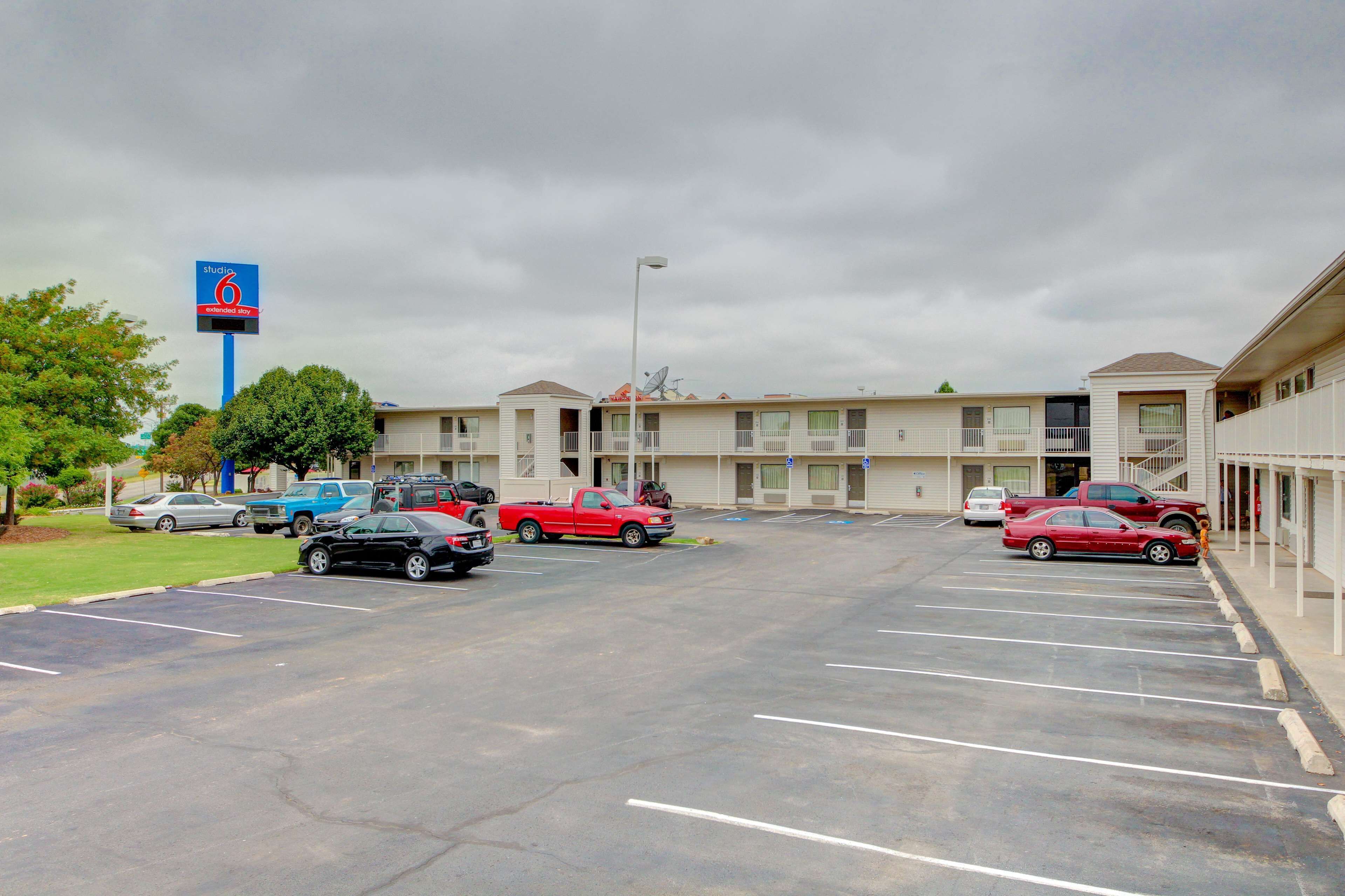 Un motel con aparcamiento, varias habitaciones y un cartel que indica el nombre y los servicios.
