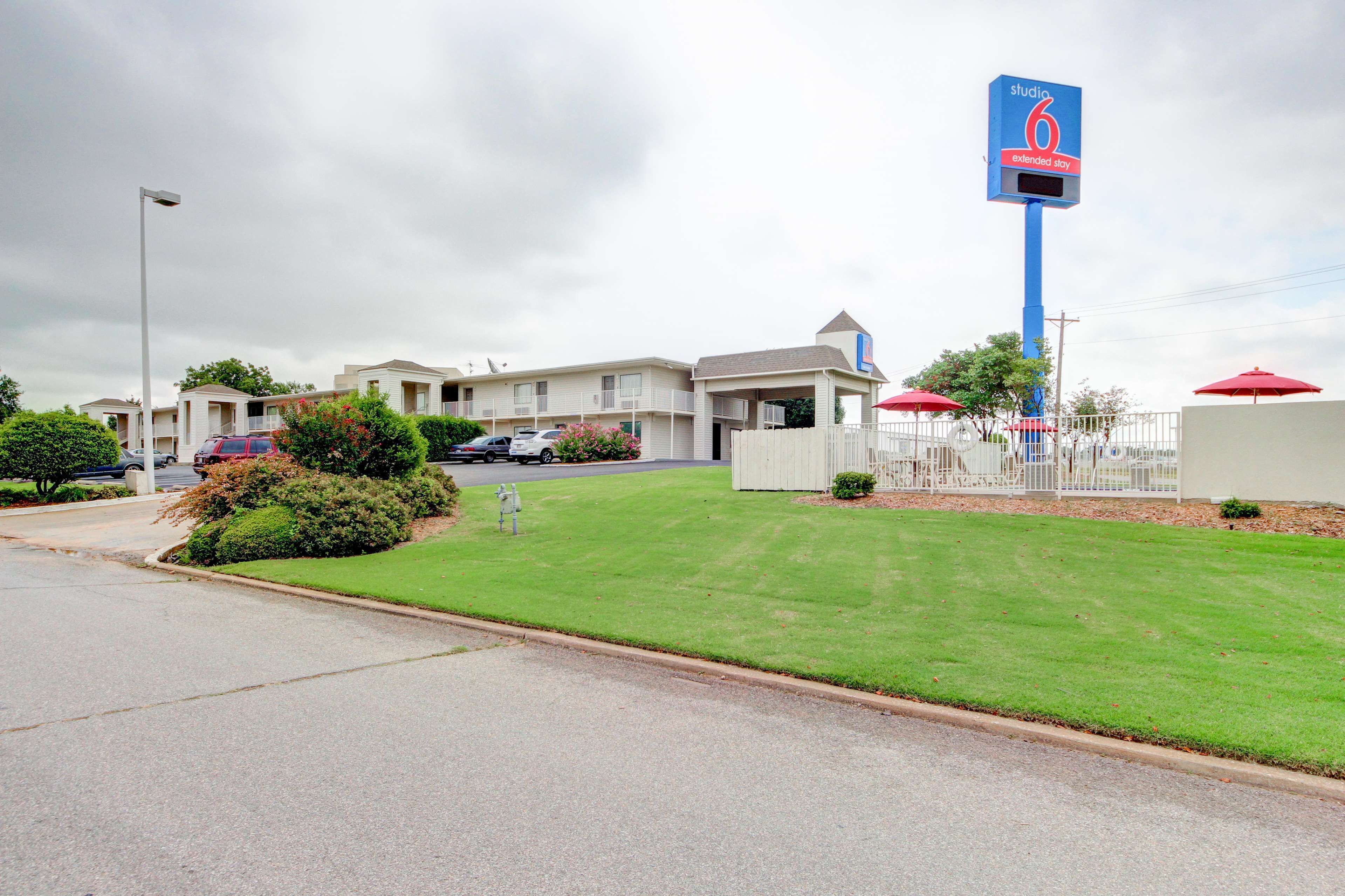 A motel with a large sign, a well-maintained lawn, and a parking area.