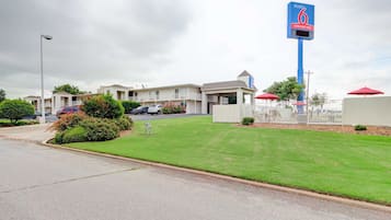 A motel with a large sign, a well-maintained lawn, and a parking area.