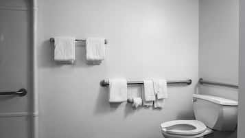 Un baño con inodoro, un perchero con varias toallas y zona de ducha.
