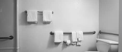 Un baño con inodoro, un perchero con varias toallas y zona de ducha.