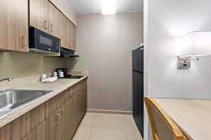 A compact kitchen with a microwave, coffee maker, and a refrigerator. - Suburban Studios Fishers Indianapolis (Fishers)