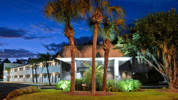 Un motel con una fila de habitaciones, palmeras y un césped bien cuidado.
