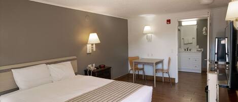 Una habitación de hotel con una cama grande, un escritorio y una kitchenette.