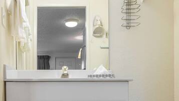 A bathroom with a white sink, a mirror, a towel rack, and a towel hanging on the wall.
