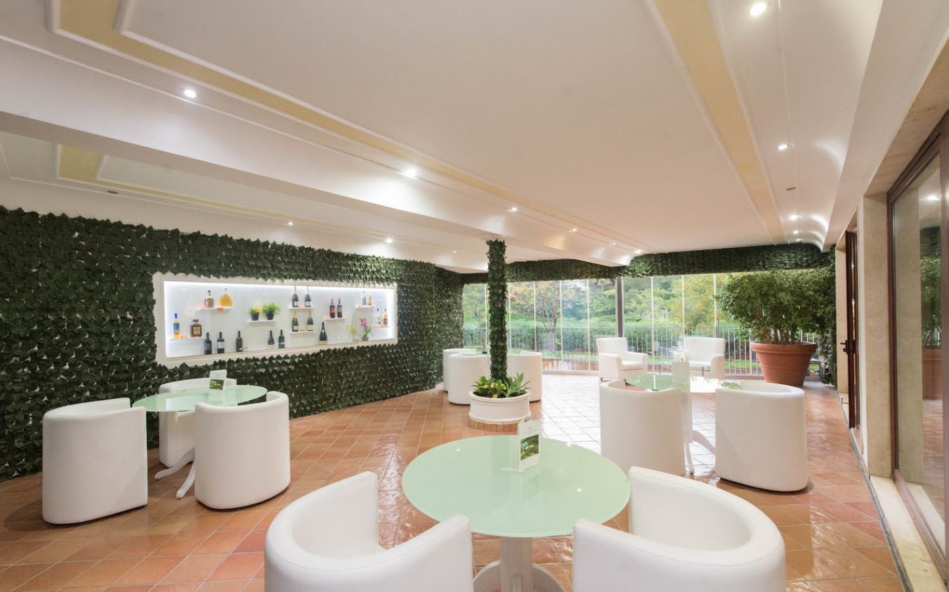 Un espace intérieur moderne agrémenté d’un mur végétal, de meubles blancs et d’une table en verre.