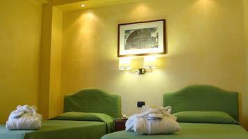 Two single beds with green bedspreads and matching headboards, a framed picture, and a wooden floor.