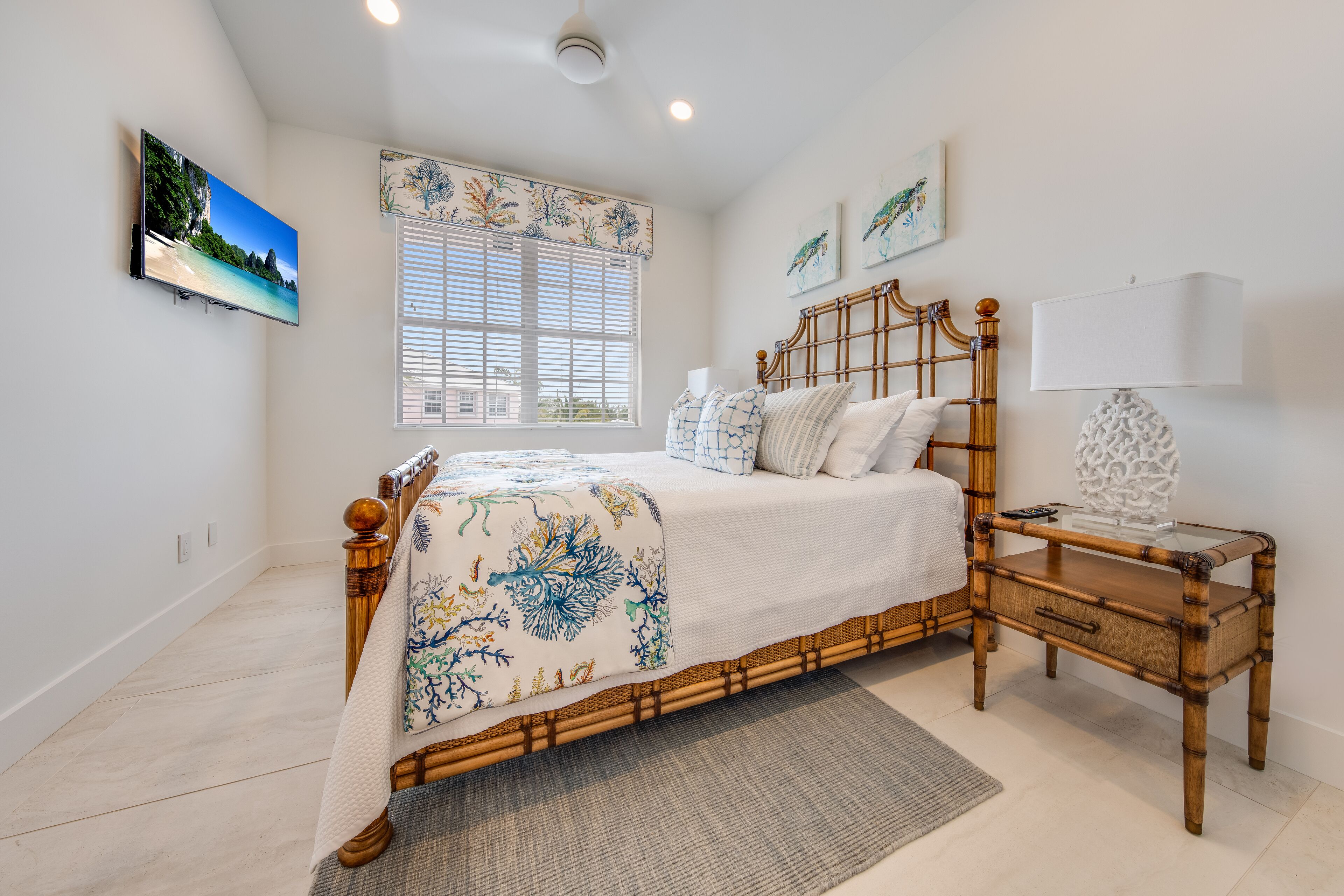 A bedroom with a bed, bedside table, lamp, and artwork on the wall.