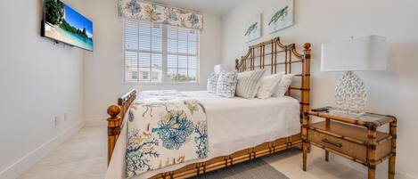 A bedroom with a bed, bedside table, lamp, and artwork on the wall.