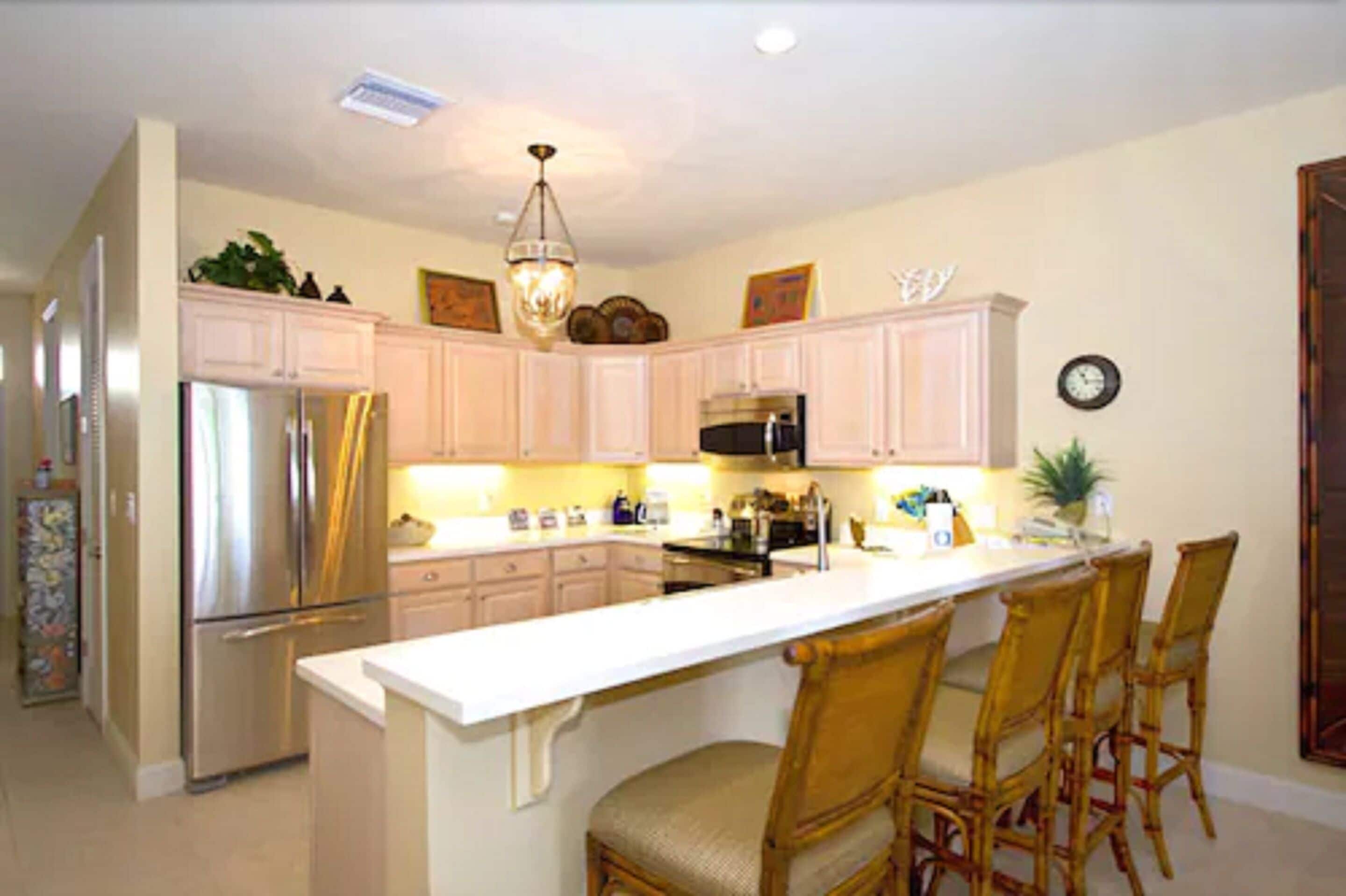 A kitchen with white cabinets, a stainless steel refrigerator, a microwave, and a dining area with four chairs.