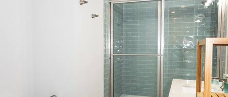 A bathroom with a white toilet, a glass-enclosed shower, and a wooden vanity.