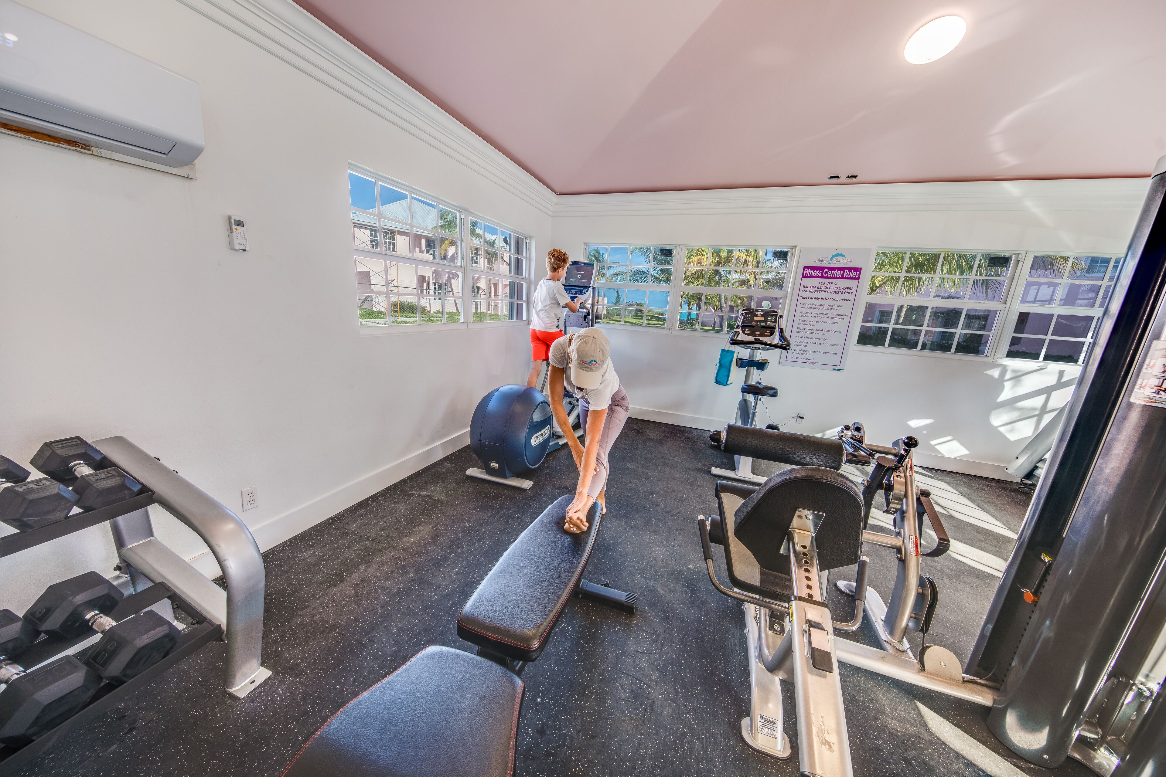 A gym with exercise equipment, a standing bike, and a window with a view of buildings.