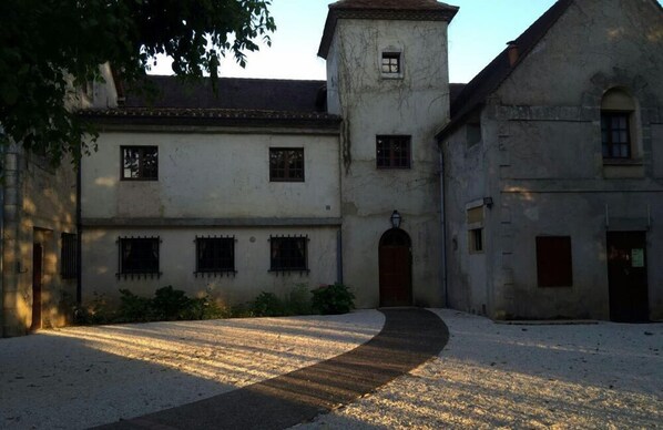 Un cortile con un edificio caratterizzato da una torre centrale e numerose finestre.