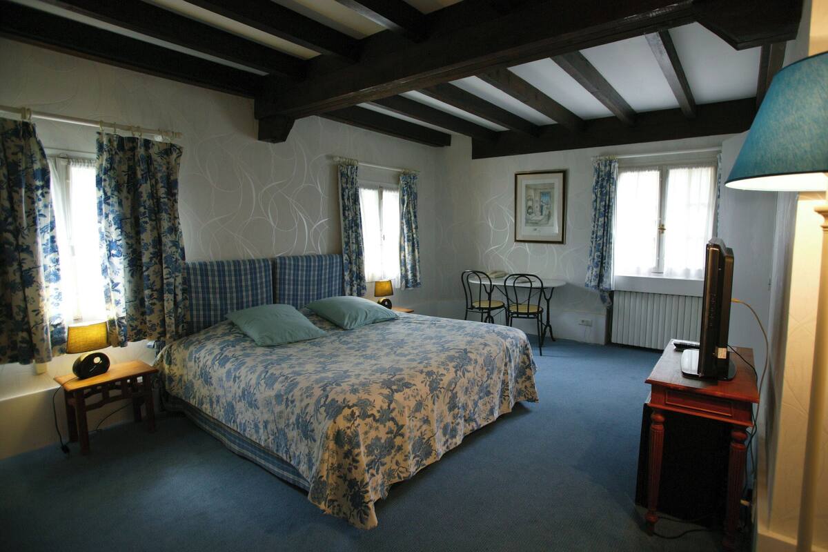A bedroom with a bed, a desk, a chair, a lamp, and a radiator.