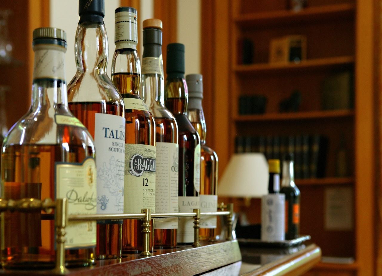 A selection of whisky bottles on a shelf, with labels visible.