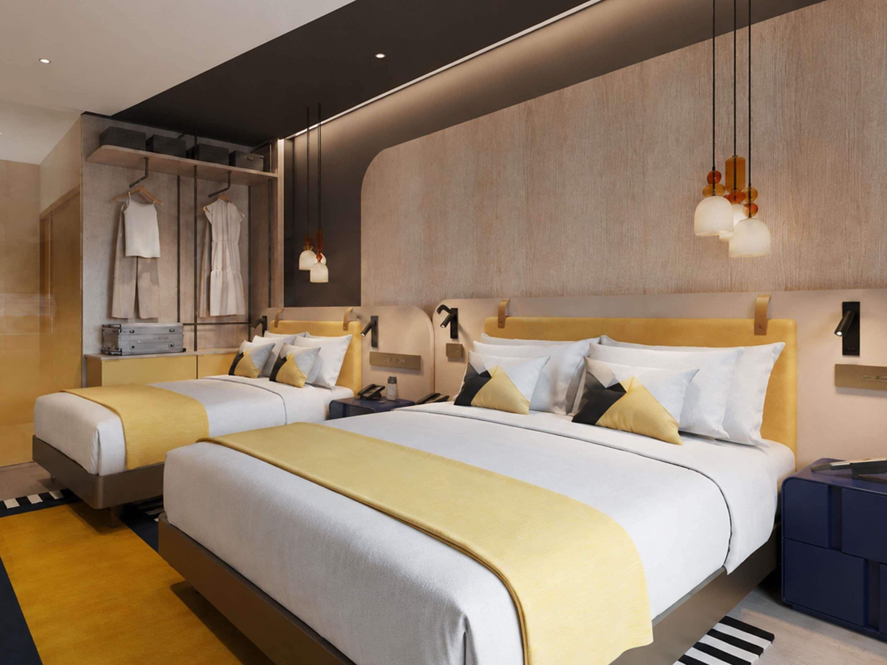 A hotel room with two beds, a wardrobe, and a bedside table.