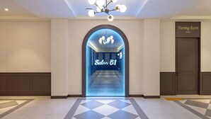 A hotel entrance with a modern design, including a geometric floor pattern and a sign for a nursing room.