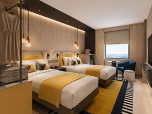 Une chambre d’hôtel moderne avec deux lits, un bureau, une chaise, une petite table et une vue sur la ville.