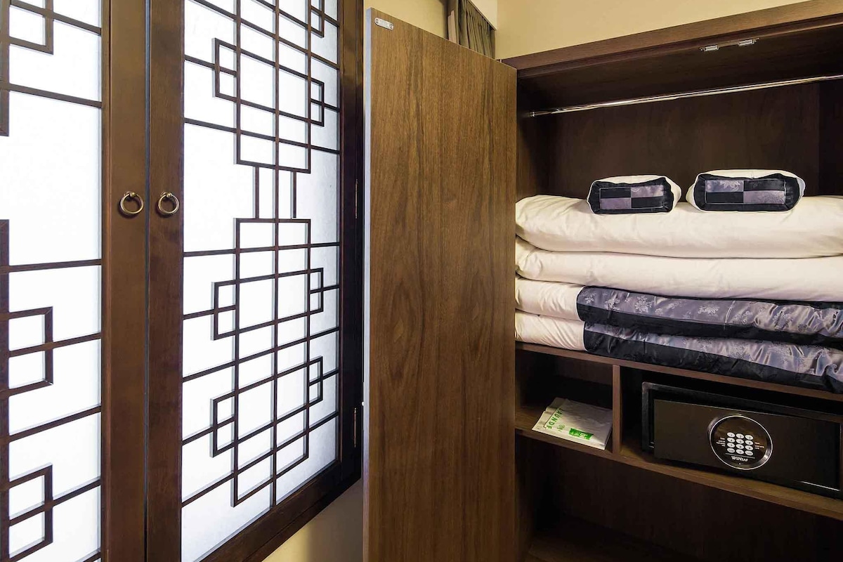 Ein Schlafzimmer mit Holzschrank, einem Bett mit vielen Kissen und einem fest eingebauten Safe.