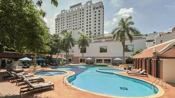 Un hôtel doté d’une piscine, de chaises longues et de palmiers.