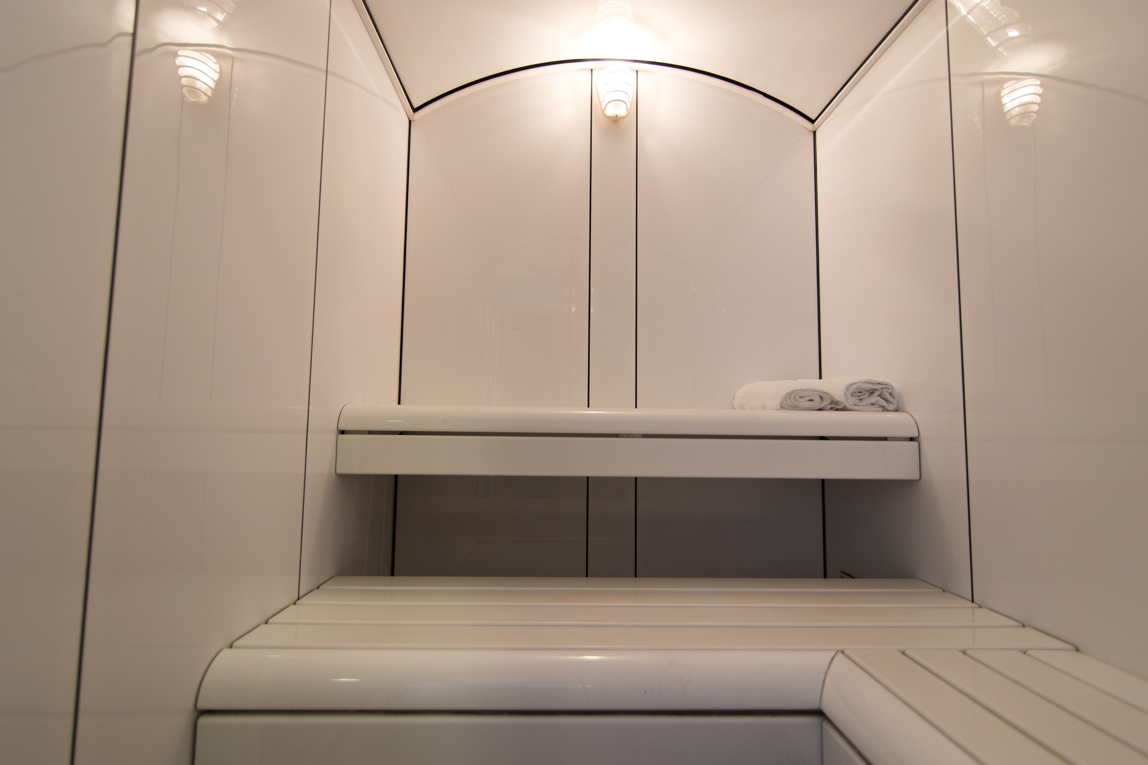 A modern, minimalist bathroom with a built-in bench, towel rack, and recessed lighting.