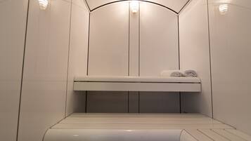 A modern, minimalist bathroom with a built-in bench, towel rack, and recessed lighting.