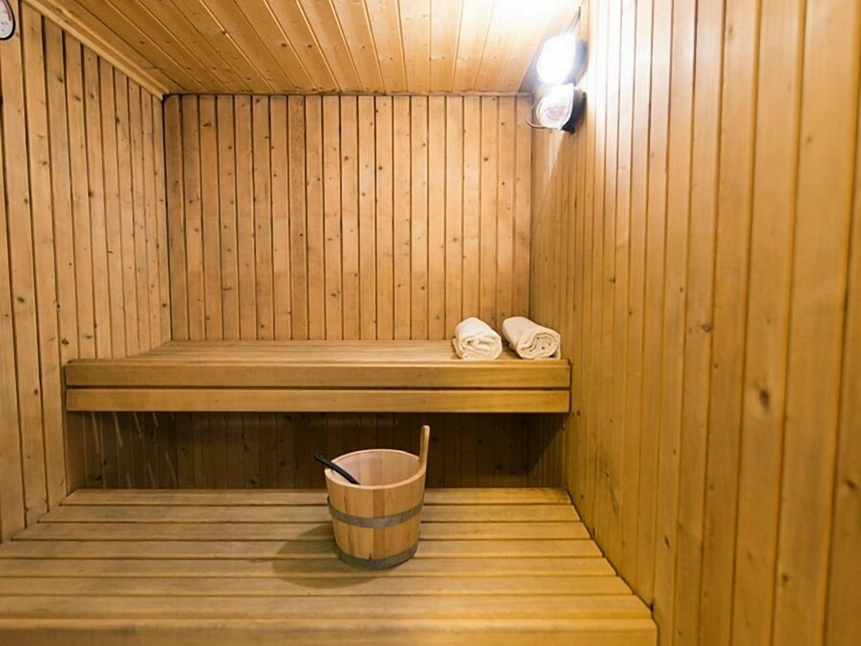 Un sauna en bois avec un banc, un seau et des serviettes.