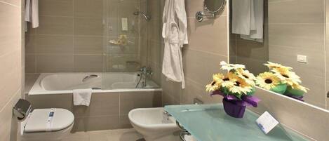 A modern bathroom with a glass shower enclosure, a bidet, a toilet, and a vanity with a glass sink.