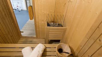 Eine Holzsauna mit Bänken und einem Eimer.