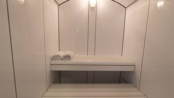 Un petit sauna fermé, équipé d’un banc et de serviettes.
