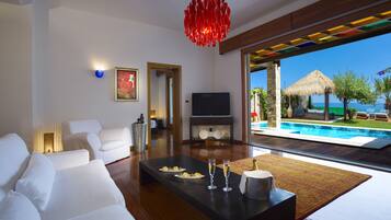 A modern living room with a large window overlooking a pool and ocean.