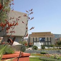 Un edificio con un cartel que dice "ACROPOLIS" y una fuente en su fachada.