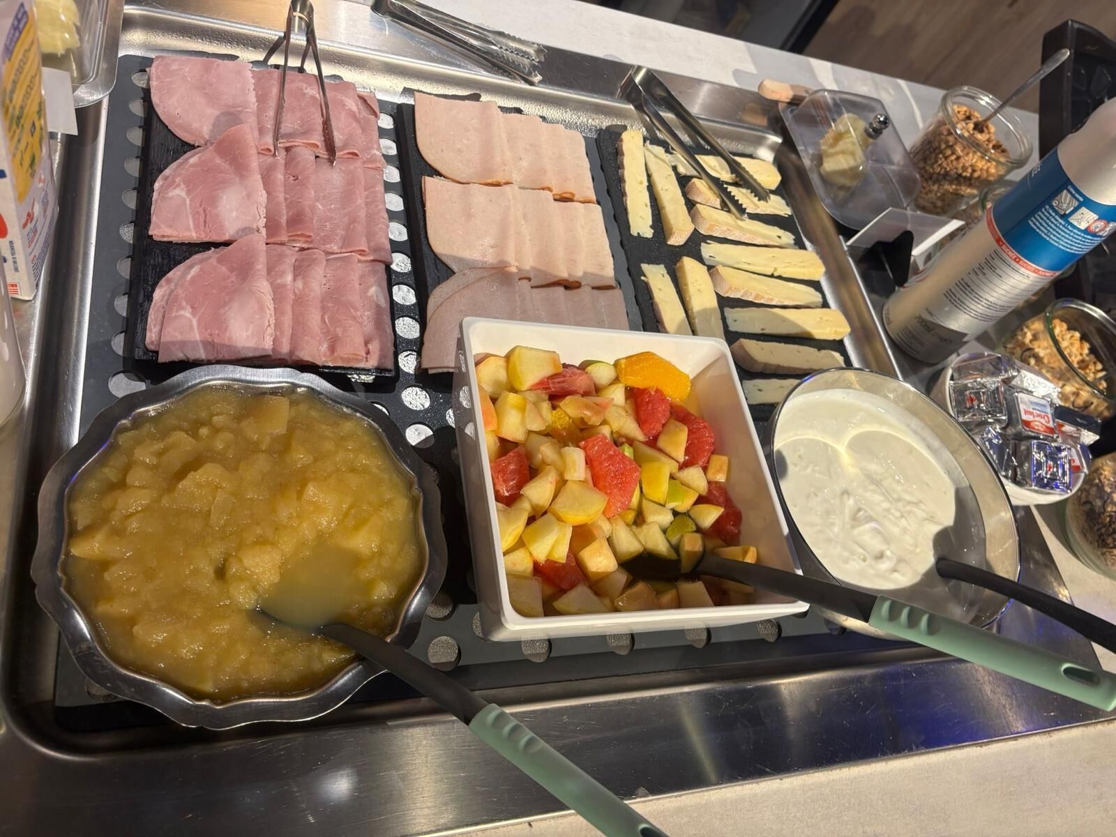A buffet with various food items including meats, fruits, and a bowl of soup.
