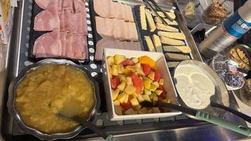 A buffet with various food items including meats, fruits, and a bowl of soup.