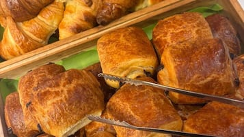 A variety of pastries, including croissants and puff pastries, displayed in wooden trays.