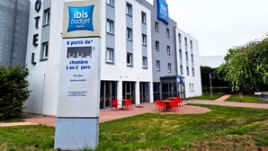 A hotel with a sign indicating it is part of the ibis budget chain, offering rooms for 1 or 2 persons, with a visible outdoor seating area. - ibis budget Lille Marcq-en-Baroeul (Marcq-en-Baroeul)