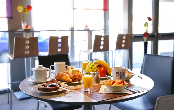 Une table de petit-déjeuner avec des croissants, des fruits et du café.