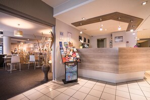 Eine moderne Hotelhalle mit Empfangstresen, Sitzgelegenheiten und einer Auswahl an lokalen Broschüren.