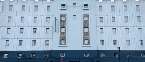 Un edificio moderno con fachada simétrica, múltiples ventanas y una entrada central con un letrero que dice "Kyriah".
