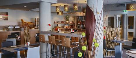 En moderne restaurant med høje borde, stole og hængende pendellamper.