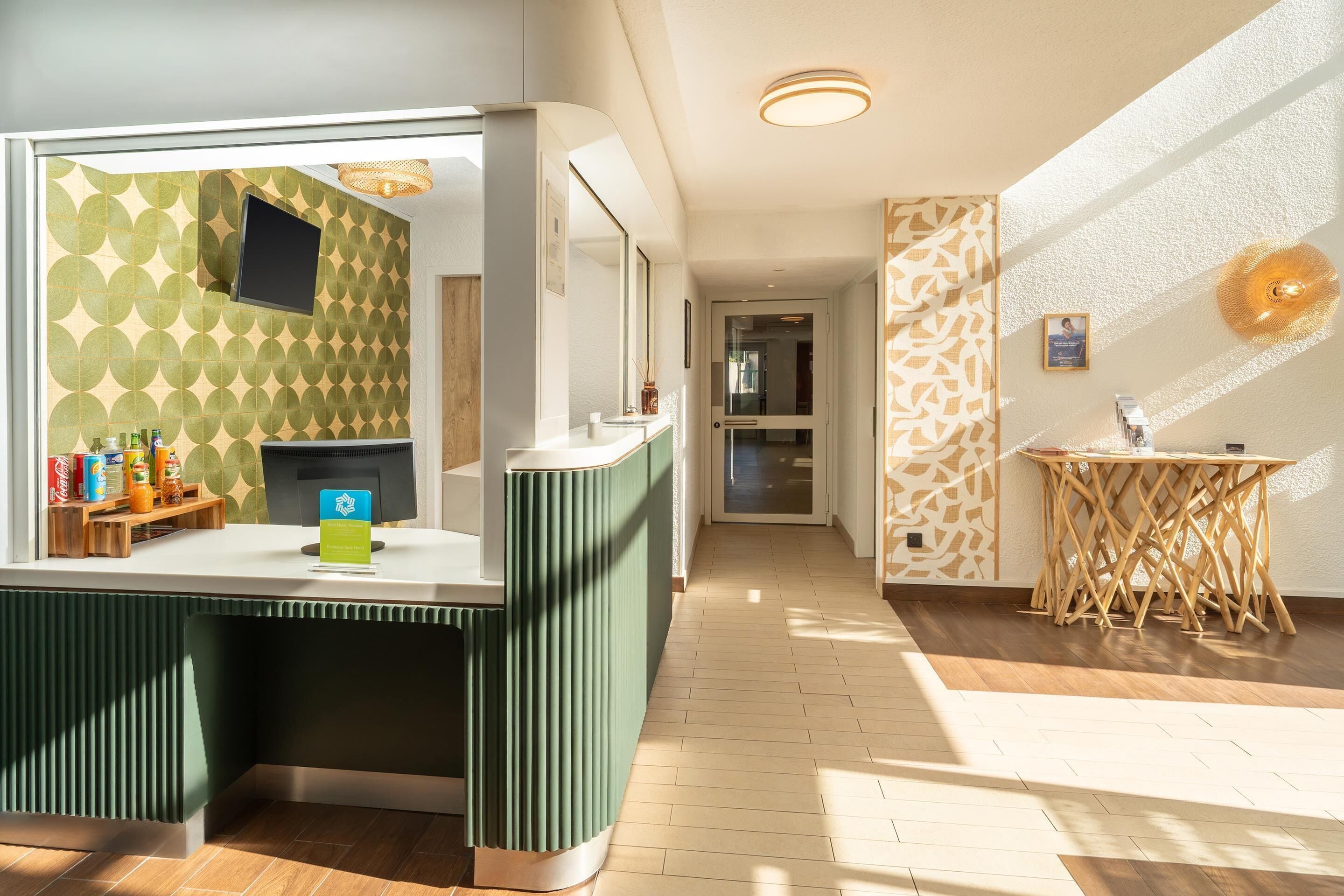 A modern reception area with a green counter, a flat-screen TV, and a patterned wall.