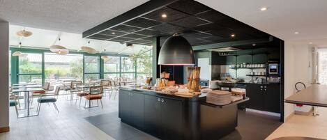 A modern kitchen with a large island, black cabinets, and a hanging light fixture.