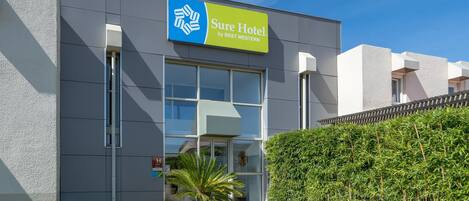 A modern hotel building with a sign reading "Sure Hotel by Best Western."