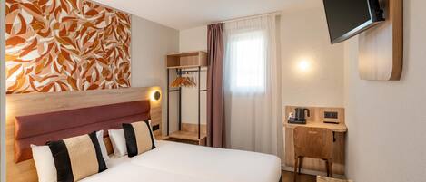 Habitación de hotel con una cama grande, un escritorio con computadora, un televisor montado en la pared y un cabecero de madera.