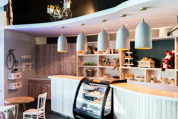 A modern cafe with a counter, a display case with pastries, and hanging pendant lights. - Grand Velas Riviera Nayarit - All Inclusive (Nuevo Nayarit)
