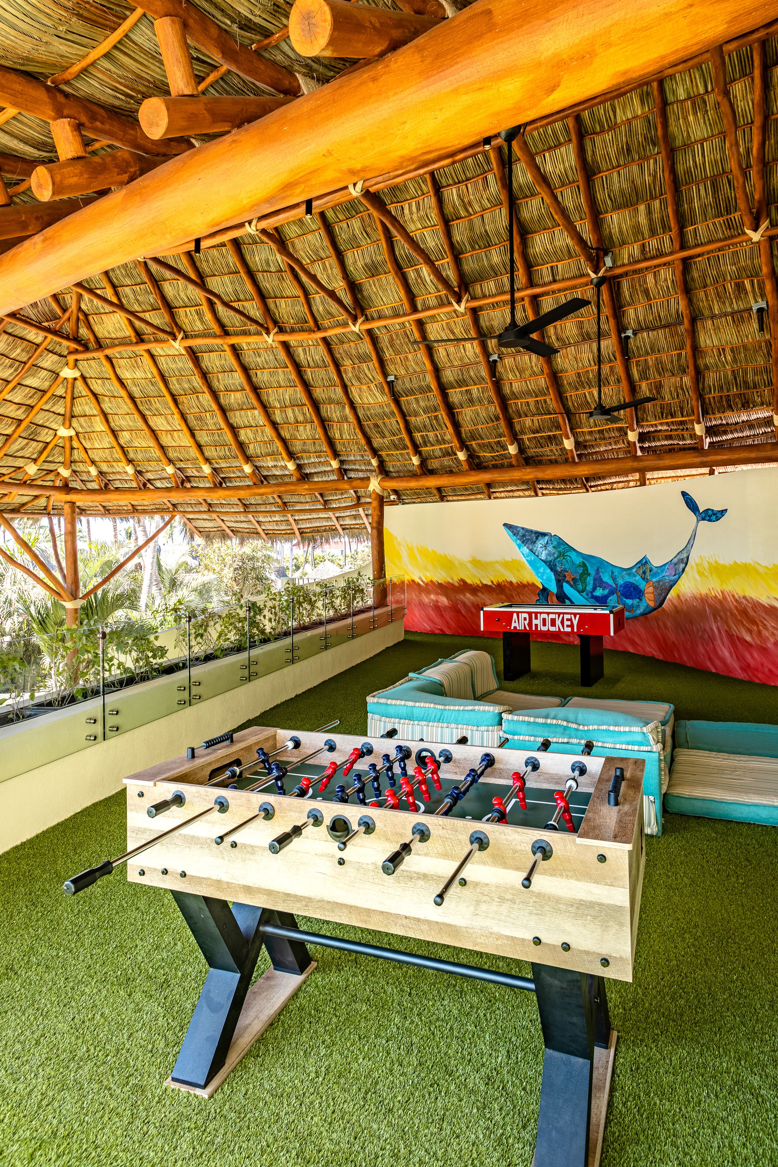 Zona interior d'esports amb una taula de futbolí, una taula de bitlles i un mural a la paret.