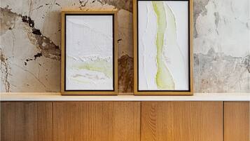 Two framed abstract paintings on a wooden cabinet against a textured wall.